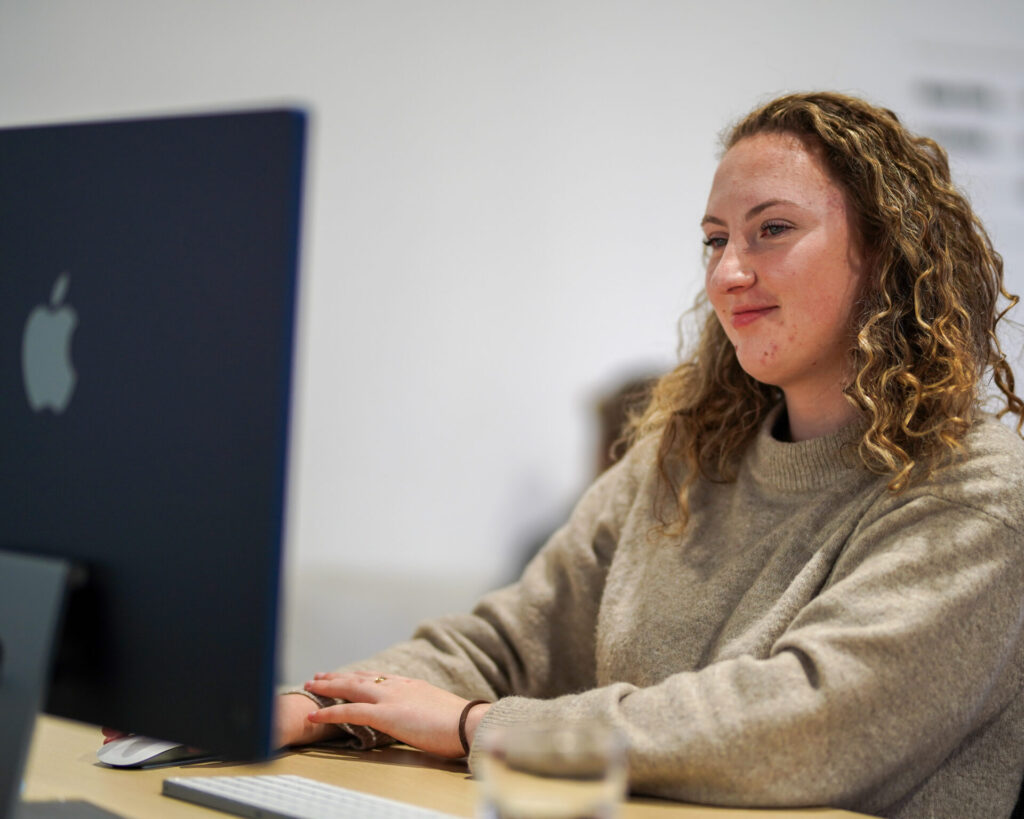 Girl sitting at her desk looking at her laptop screen in a digital marketing agency